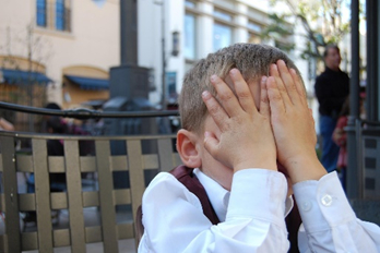 Image of a young child covering their face with their hands
